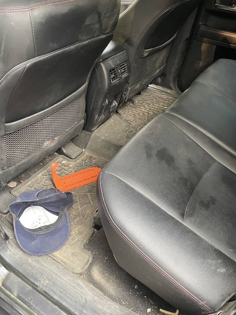 Toyota 4Runner TRD Pro rear footwells before detailing — a cap, a traction board and grit across the mats