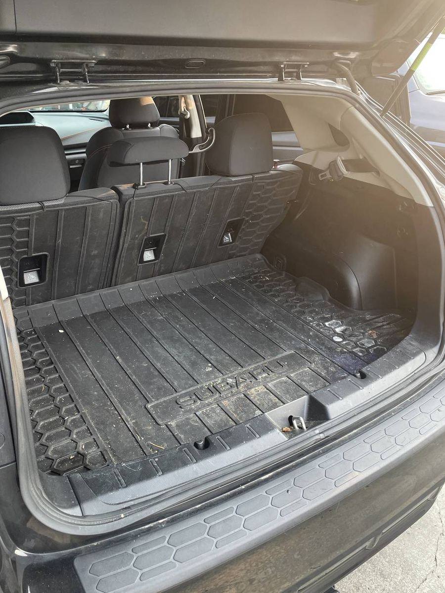 Subaru Crosstrek cargo area before detailing — dust and debris across the rubber liner