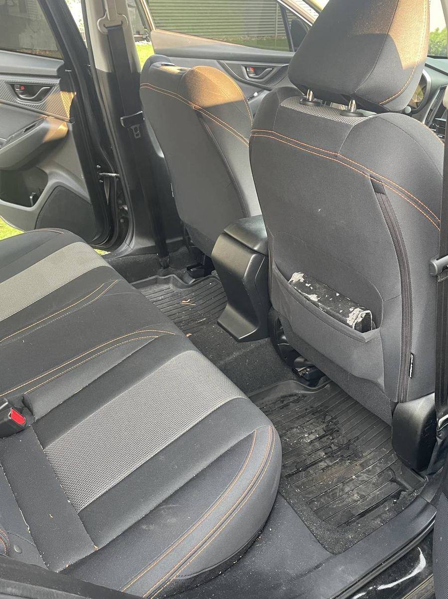 Subaru Crosstrek rear seats before detailing — debris in the seat pocket and across the floor